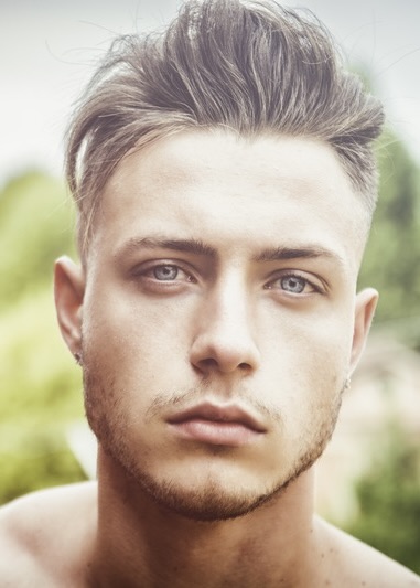 Close-up portrait of a young man with stylish hair and a serious expression.